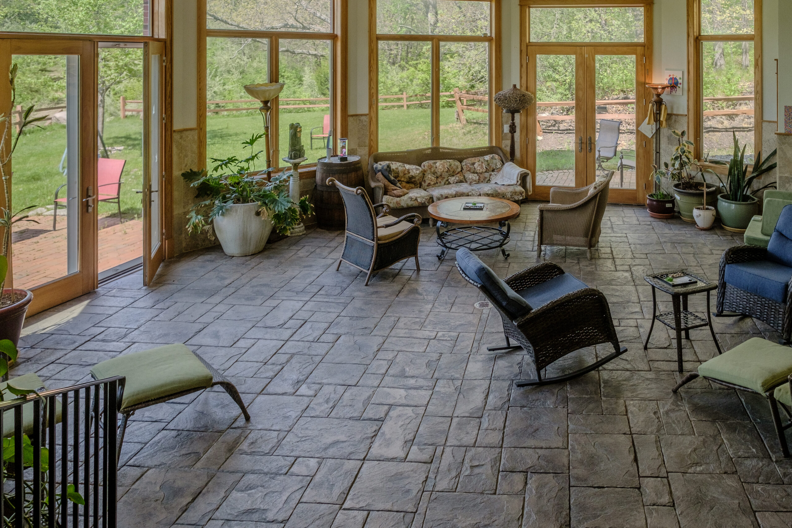 Stunning 12-foot-high atrium with large windows overlooking woods and water at Top of the World Ranch Milan IL, a sunlit relaxation space in the Main Lodge for healing and reflection.